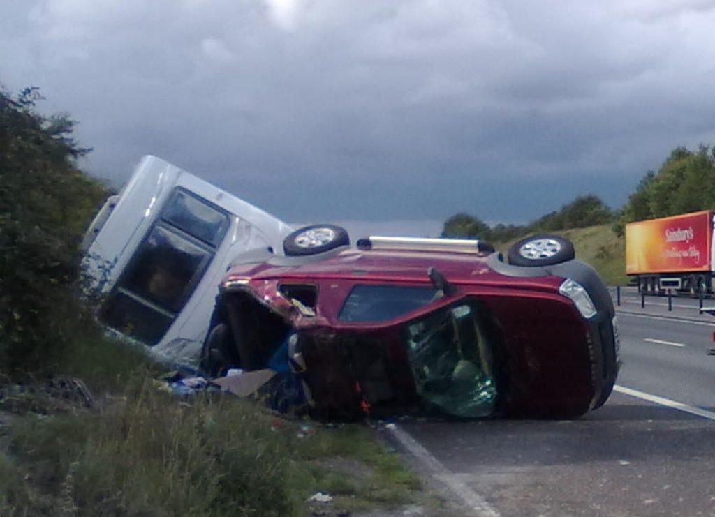 A caravan and overturned car on a motorway hard shoulder after a towing accident, the kind of caravan recovery I handle