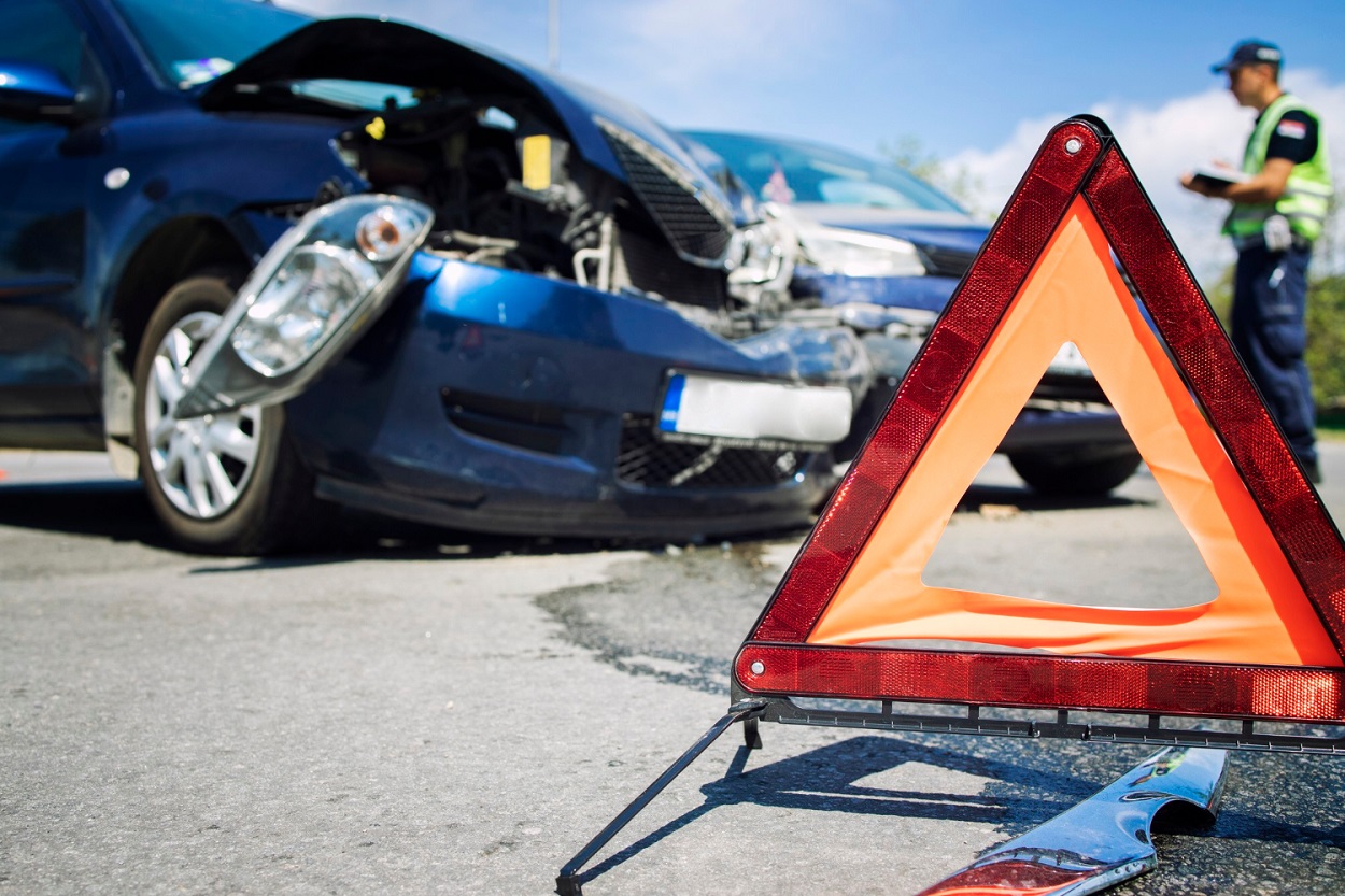 Damaged car at the roadside after a collision, with a warning triangle placed behind it