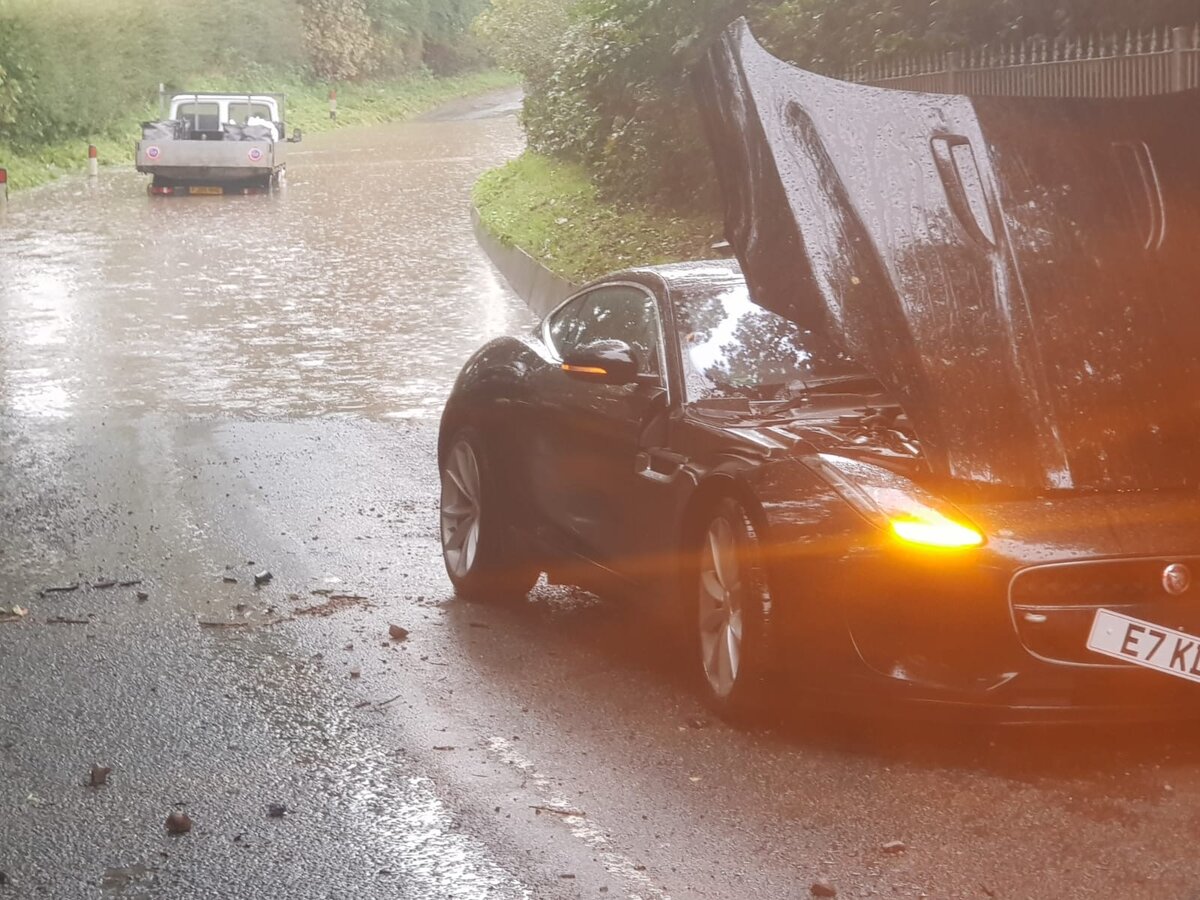 Black Jaguar F-Type with bonnet up and hazards on at the roadside during a breakdown callout.
