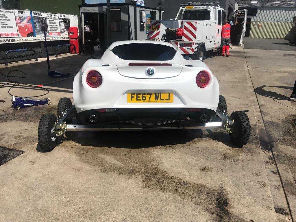 Stranded Alfa Romeo 4C lifted onto recovery dollies at the Breakdown Man depot, ready for transport.