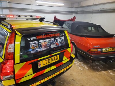 Breakdown Man's liveried 24/7 recovery car parked beside a red Saab convertible.