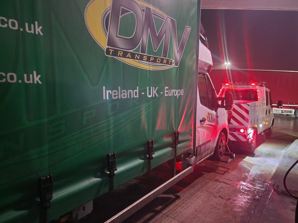 White Renault Master van being recovered onto Breakdown Man's flatbed beside a DMV Transport curtainsider trailer at night.