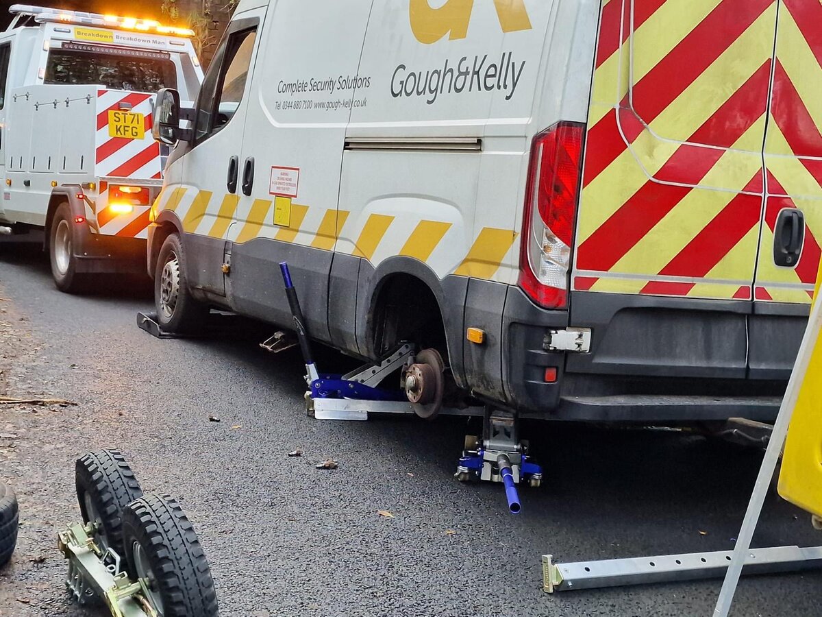 Gough & Kelly white Iveco security van raised on bottle jacks for rear-wheel removal beside Breakdown Man's ST71 KFG recovery truck.