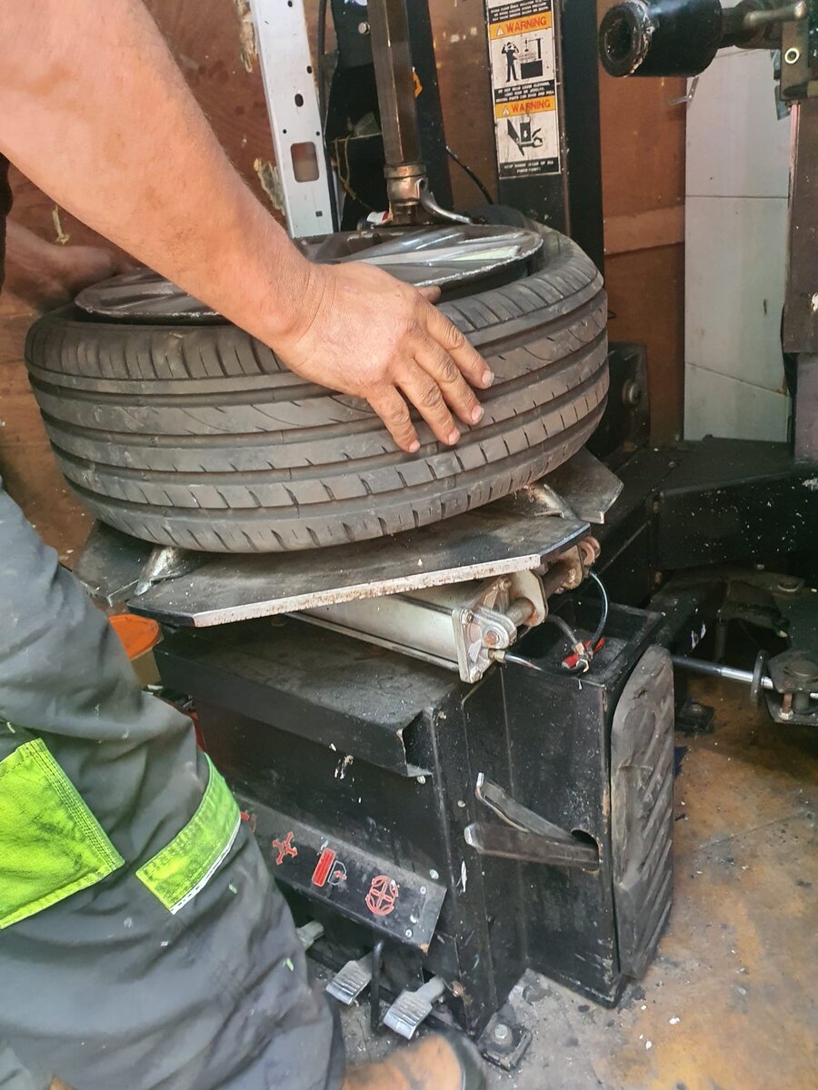 Close-up of a Breakdown Man operator's hands fitting a tyre on a tyre changer machine, mobile tyre service near Hindley.