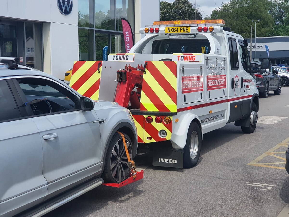 Silver Volkswagen T-Roc SUV being loaded onto a Breakdown Man Iveco recovery truck outside a VW dealership on the way back to Leigh.