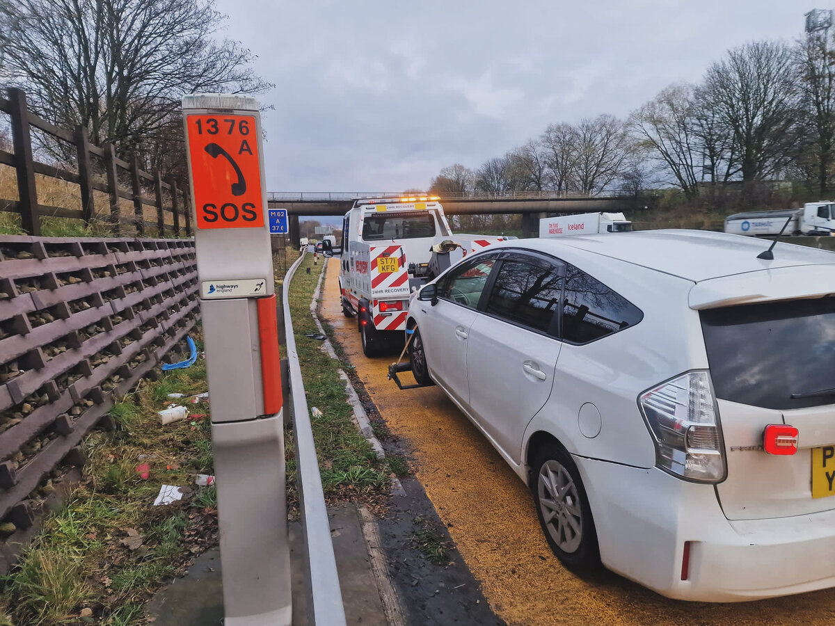 Breakdown Man recovering a white Toyota by motorway SOS phone 1376A on the M61/M62 chevrons.
