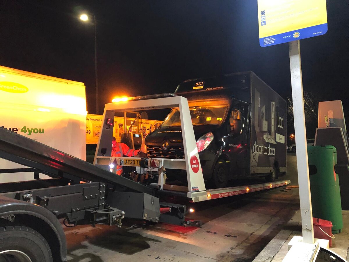 Breakdown Man flatbed loading a mis-fuelled vehicle at a petrol station at night for transport off the forecourt