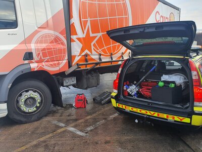 Breakdown Man recovery car with its boot open showing recovery kit beside an HGV during a roadside assist.