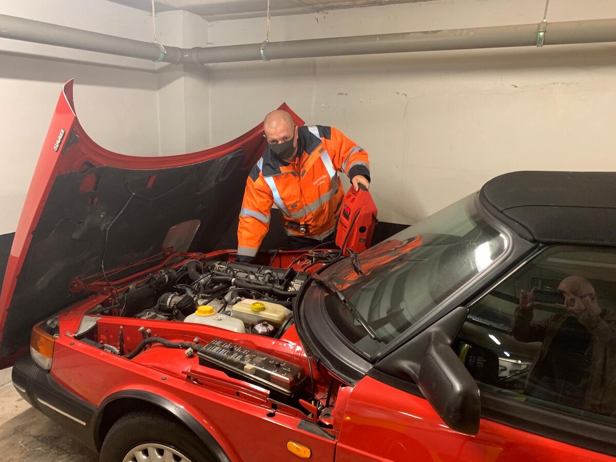 Simon in hi-vis using a red Snap-on jump pack on a red Saab convertible with the bonnet open.