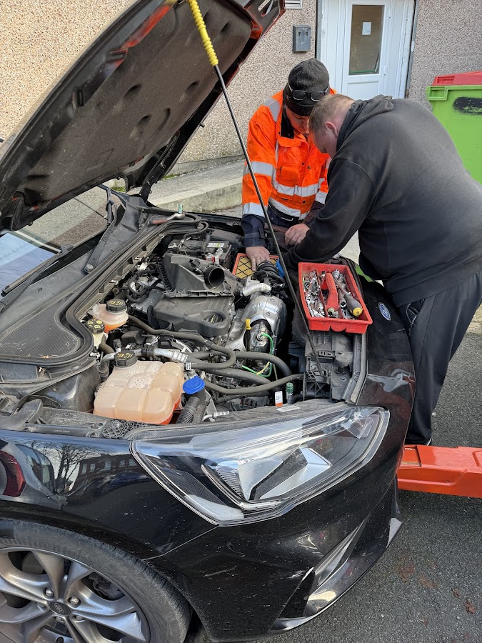Simon performing an under-bonnet roadside repair.