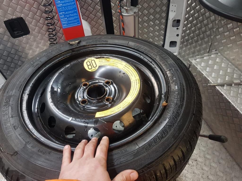 Spare steel wheel and tyre laid out at the rear of the van ready for fitting
