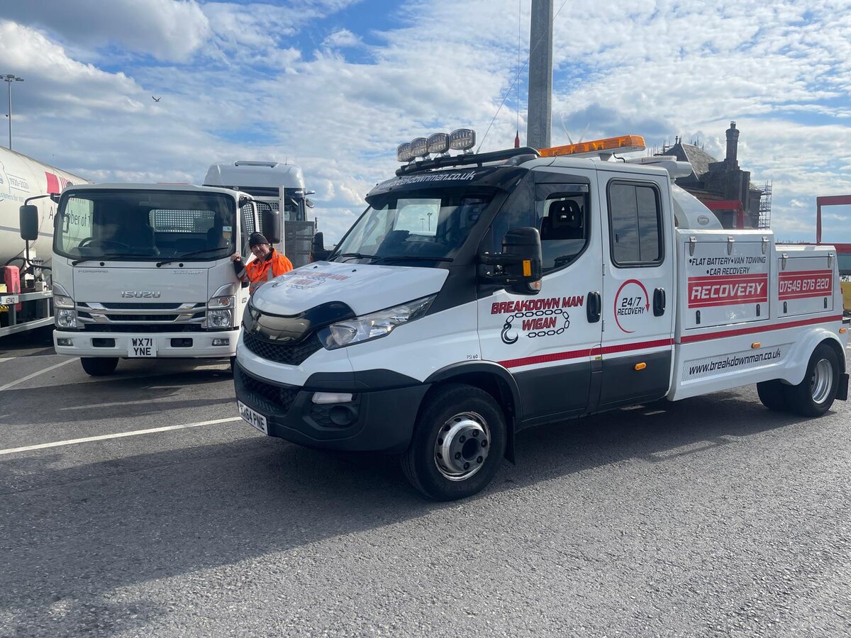White Breakdown Man Wigan Iveco 24/7 Recovery truck on the road with another flatbed in the background, ready for the next Wigan-area callout.