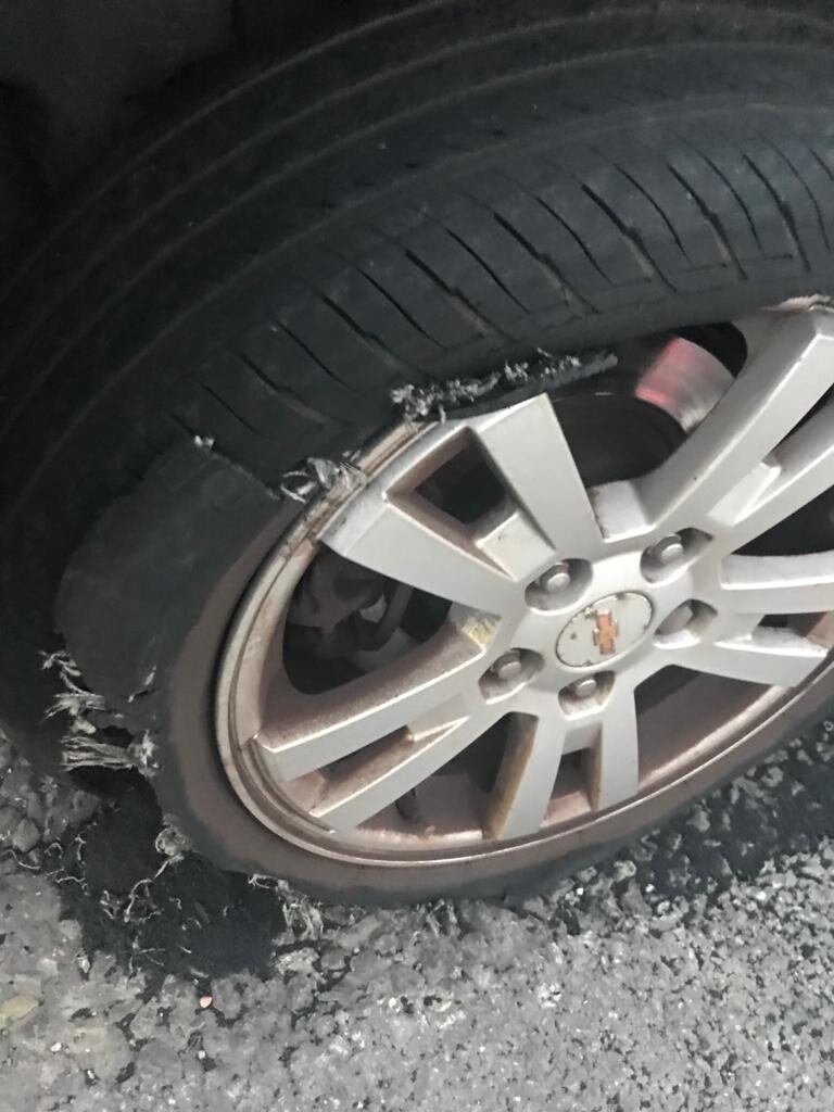 A car alloy wheel with a badly blown-out tyre at the kerbside.