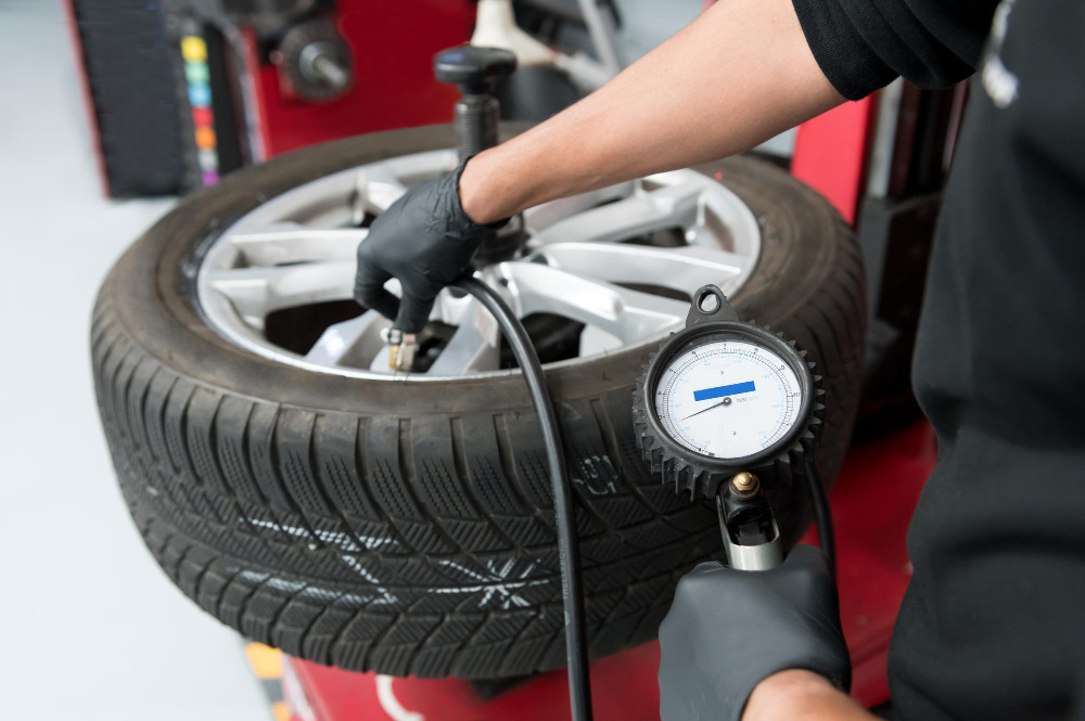 A hand-held tyre pressure gauge being used on an alloy wheel
