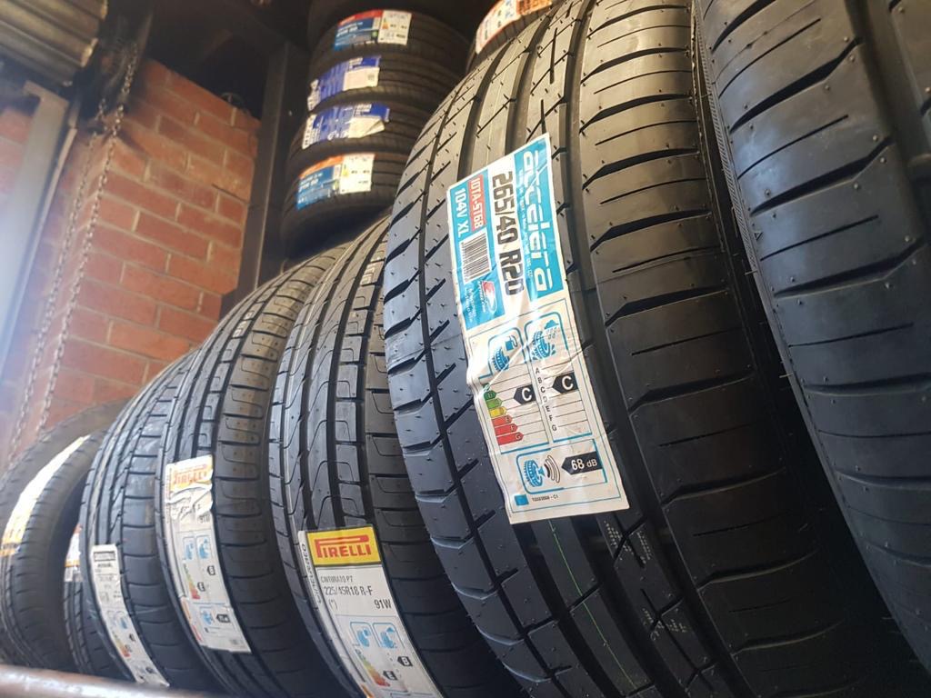 Mixed-brand car tyres on a workshop rack with EU energy labels